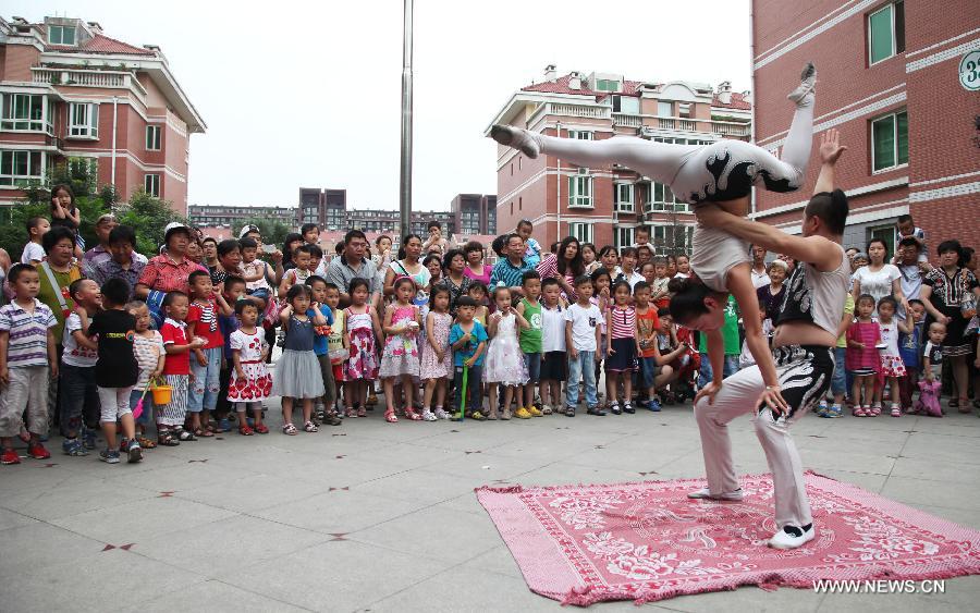 Citizens watch an acrobatic performance during a cultural activity at a community in Tongzhou District, Beijing, capital of China, June 18, 2013. (Xinhua/Bu Xiangdong) 