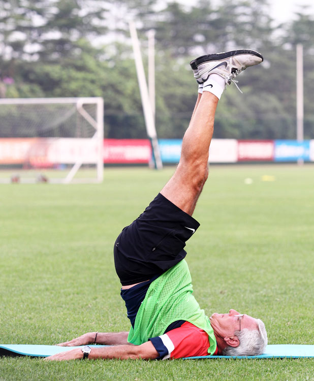 Marcello Lippi does the high challenge stretch exercise in the preparation training of Guangzhou Evergrande, June 18, 2013. (Photo/Osports)