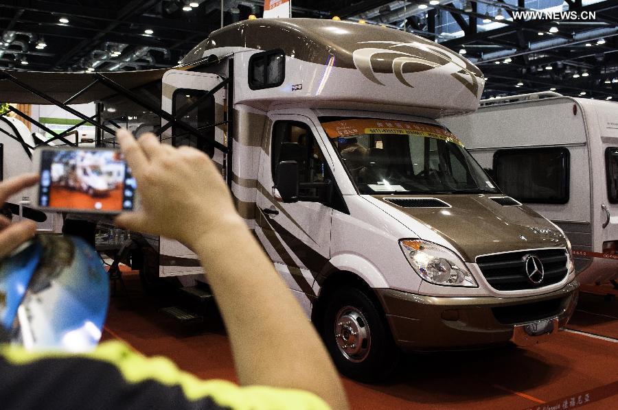 A visitor takes pictures of an RV at the Beijing International Tourism Expo (BITE) 2013 in Beijing, capital of China, June 21, 2013. The BITE 2013 kicked off on Friday, attracting 887 exhibitors from 81 countries and regions. [Photo: Xinhua/Liu Jinhai] 