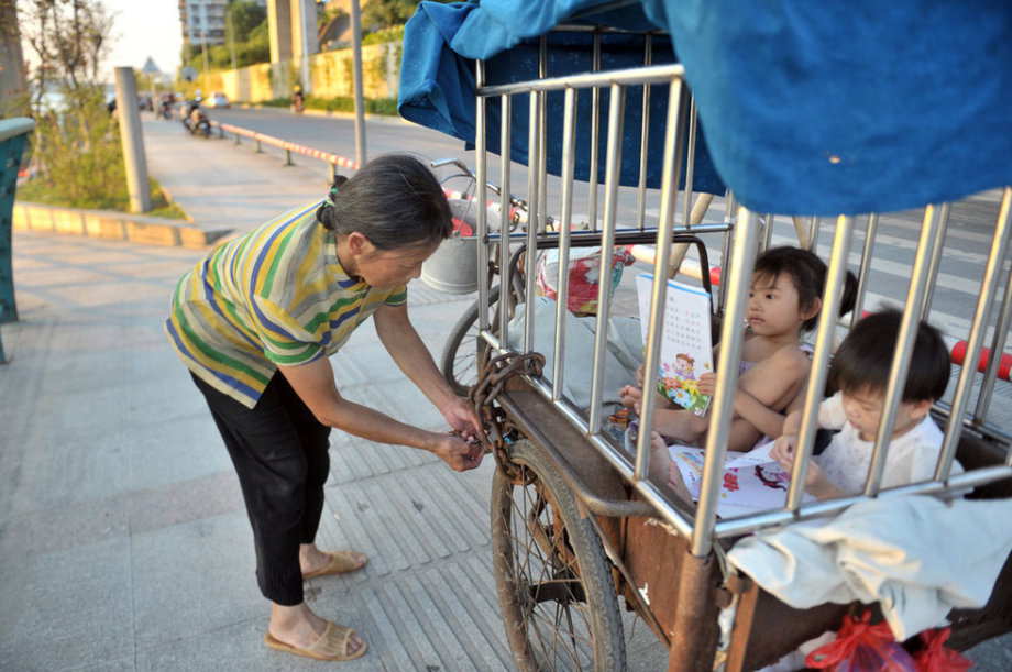 The grandmother locks the two girls up before she goes to do laundry by the river in S China’s Guangxi June 18, 2013. (Photo/ youth.cn)