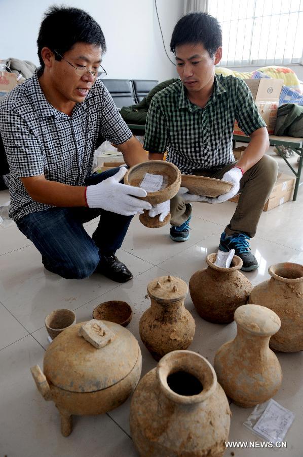 Archaeologists sort unearthed relics at Guxiang Township in Linying County, central China's Henan Province, June 22, 2013. Chinese archaeologists have discovered a well-reserved large burial complex dating back to the Warring States Period (475-221 BC) and the West Han (206 B.C.--25 AD.) Dynasty along the local section of the south-to-north water diversion project recently. Some 412 cultural relics have been unearthed in 119 excavated tombs. (Xinhua/Zhu Xiang)