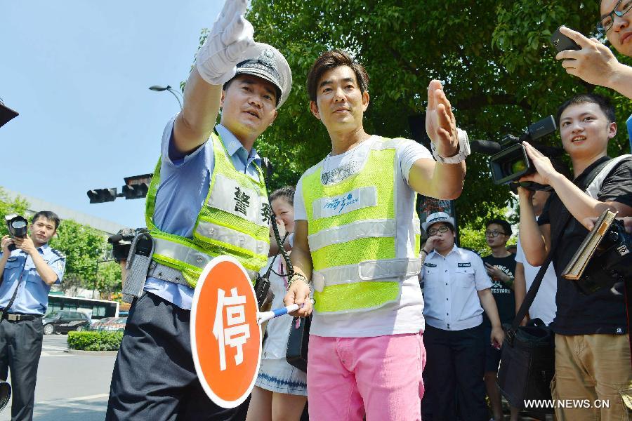 Richie Jen (center right), singer and actor of southeast China's Taiwan, volunteers as a traffic warden for a local campaign promoting civilized traffic in Hangzhou, capital of east China's Zhejiang Province, June 17, 2013. (Xinhua/Long Wei) 