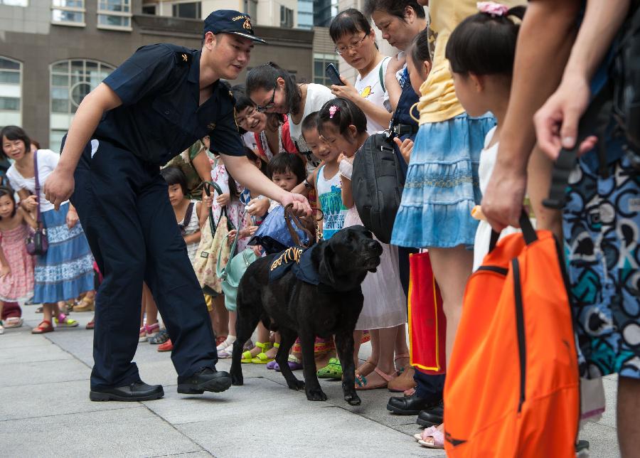 Visitors watch a detection dog performing during an "open day" of the Customs in Guangzhou, capital of south China's Guangdong Province, June 23, 2013. An "open day" activity was held here for the residents to know about the works of drug-sniffing dogs. (Xinhua/Mao Siqian)  