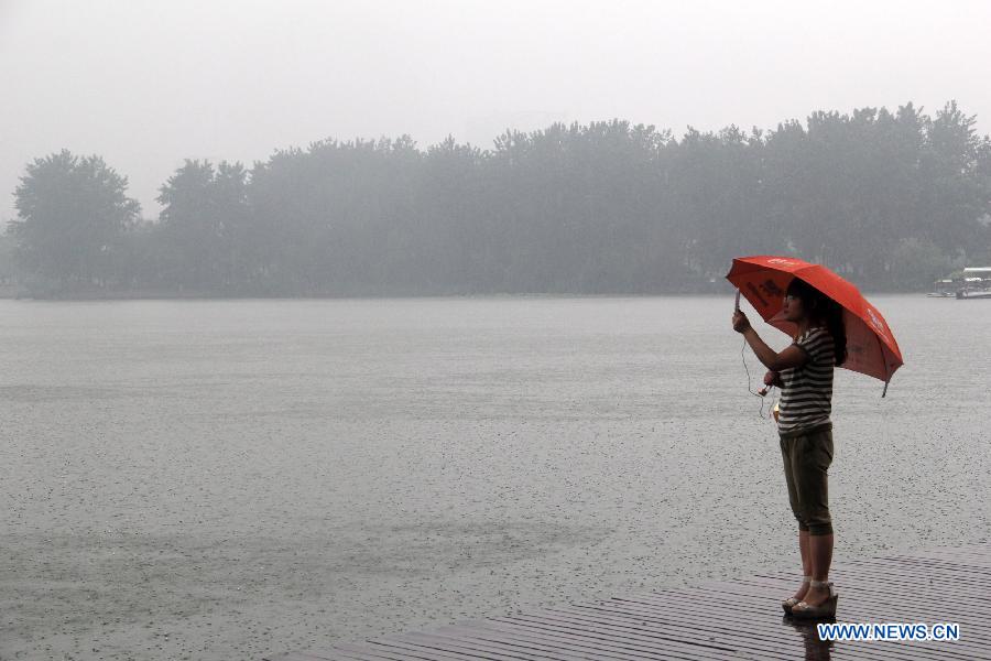 A tourist takes photos in the rain in Nanjing, capital of east China's Jiangsu Province, June 23, 2013. (Xinhua/Wang Shengtao) 