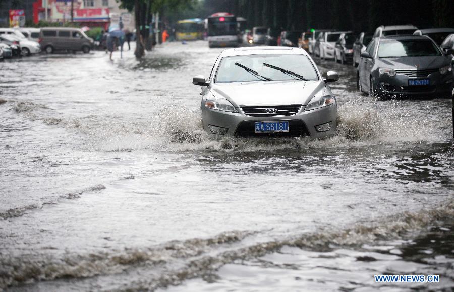 A car moves on the waterlogged road in Nanjing, capital of east China's Jiangsu Province, June 23, 2013. (Xinhua) 