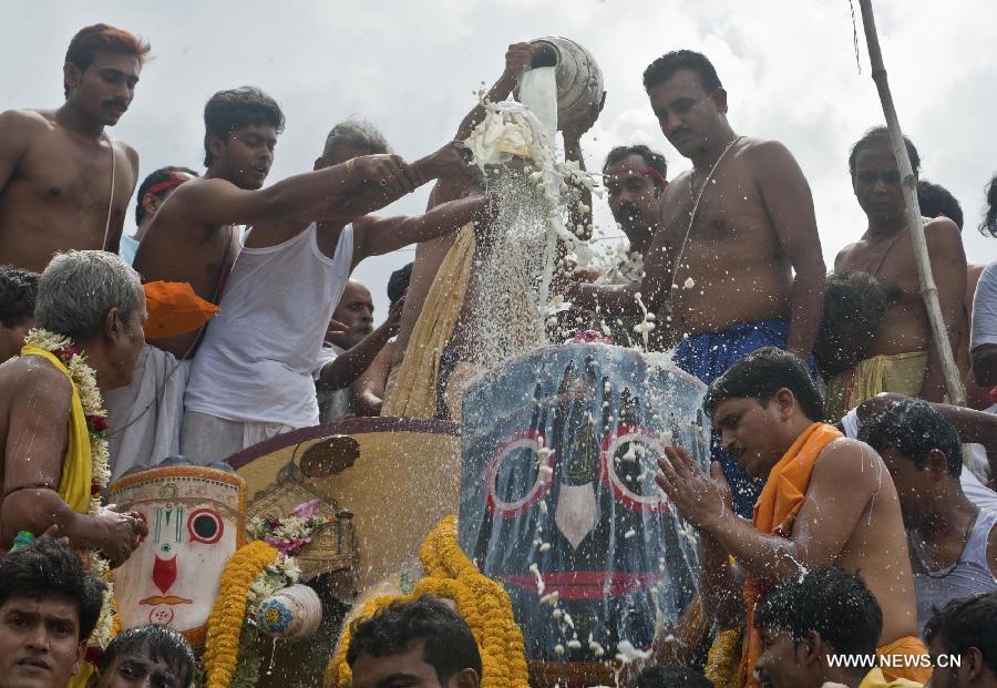 Indian priests pour milk and water during the holy bathing ceremony of Lord Jagannath at a temple near Calcutta, capital of eastern Indian state West Bengal, on June 23, 2013. (Xinhua/Tumpa Mondal)