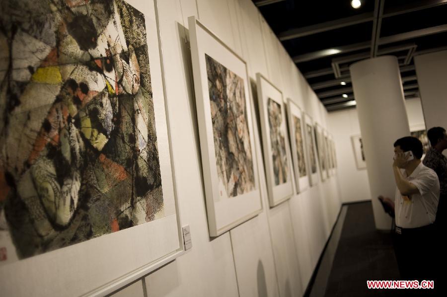 A visitor watches the exhibited paintings on a gallery show in Hong Kong, south China, June, 24, 2013. A gallery show exhibition of the paintings created by artist Xiao Jiahong opened here on Monday. (Xinhua/Lui Siu Wai)