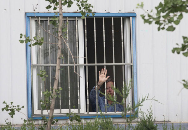 American Chip Starnes, co-owner of Specialty Medical Supplies, waves from a window of an office where he says he's been "kidnapped" by Chinese workers inside his plant on the outskirts of Beijing, June 24, 2013. [Photo/Xinhua]