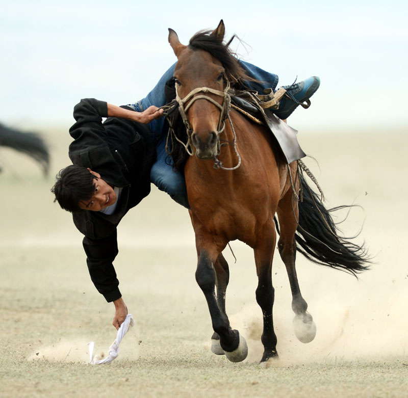 A herdsman of the Kazakh ethnic group picks up silk on the ground while riding a horse in a traditional Kazakh sports contest on June 17, 2013. During the three-day-long culture and tourism festival, nearly 200 people took parts in various contests such as horse racing and wrestling in Xinjiang's Ili Kazak autonomous prefecture. (Photo by Sha Dati/ Xinhua) 