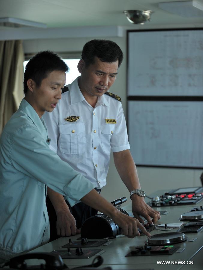 A staff member on the "Xinhai No. 19" ro-ro passenger ship which ferries along the Qiongzhou Strait and an officer from the marine bureau of Haikou, capital of in south China's Hainan Province, debug equipment on the ship, June 25, 2013. June 25 marks the third International Day of the Seafarer. (Xinhua/Zhao Yingquan) 
