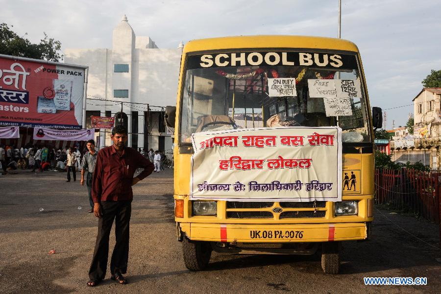 A driver stands next to a school bus for free transit in Haridwar, northern Indian state of Uttarakhand, June 25, 2013. The heaviest monsoon rains in the state for the past 60 years, which trigered deadly floods in northern India, has claimed up to 807 lives, according to Indian Authorities on Tuesday. (Xinhua/Zheng Huansong)