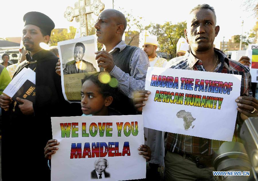 People gather outside the hospital where South Africa's anti-apartheid icon Nelson Mandela is treated in Pretoria, South Africa, to pray for Mandela, June 26, 2013. South Africa's President Zuma said on Wednesday that Mandela's condition "remains in a critical condition in hospital we must keep him and the family in our thoughts and prayers every minute." (Xinhua/Li Qihua)