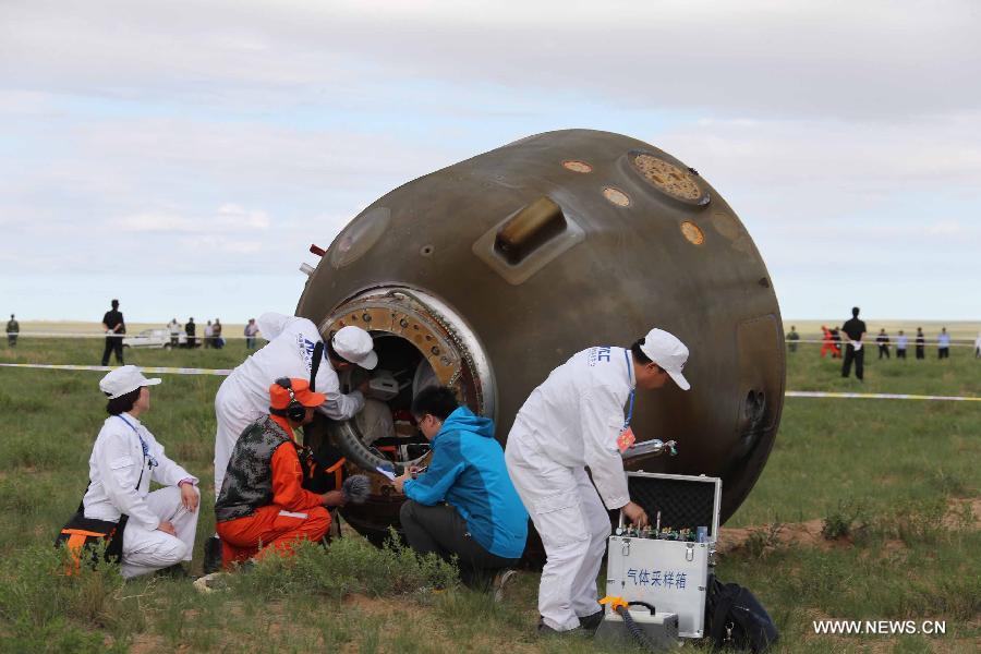 Staff members open the re-entry capsule of China's Shenzhou-10 spacecraft after its landing at the main landing site in north China's Inner Mongolia Autonomous Region on June 26, 2013. (Xinhua/Wang Jianmin)