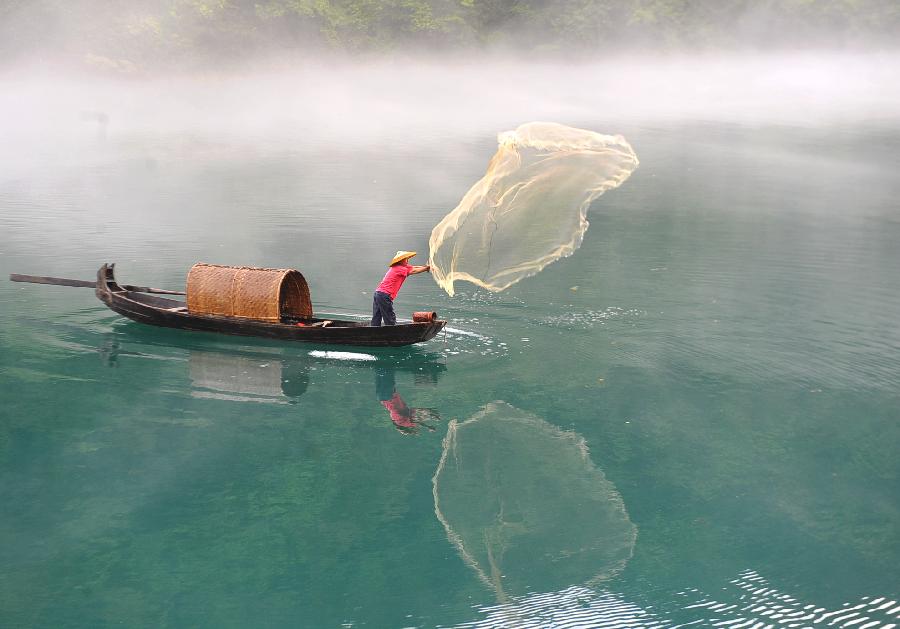 A fisherman casts a net on the fog-enveloped Xiaodongjiang River in Zixing City of central China's Hunan Province, June 25, 2013. (Xinhua/Chen Haining) 