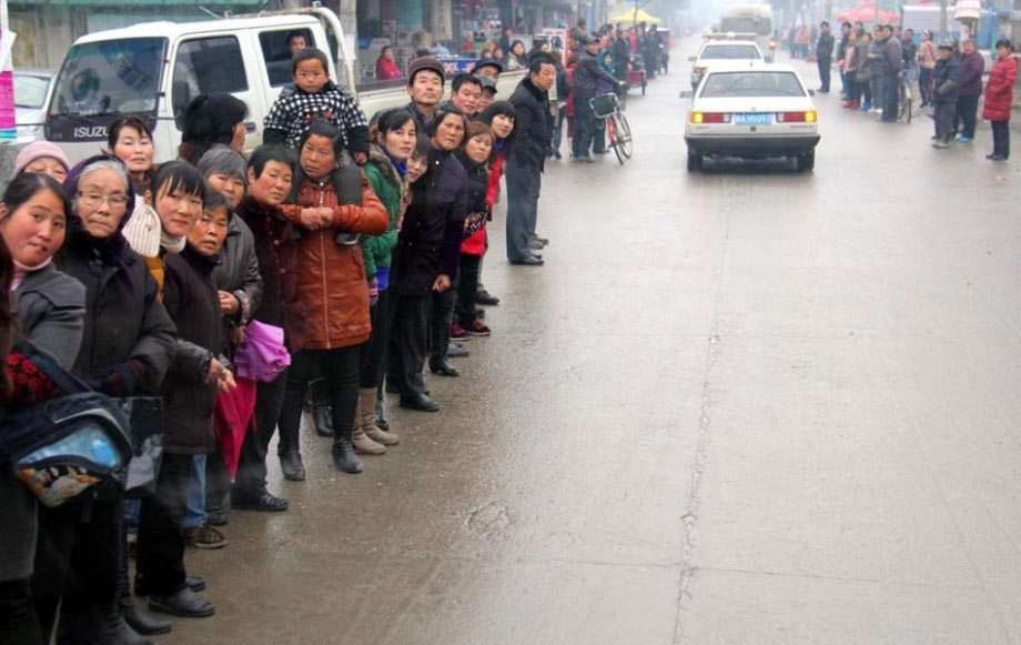 A murder suspect escorted by policy officers identifies the crime scene in Anhui on Feb. 21, 2012, attracting a crowd of onlookers. (Photo/CNTV)