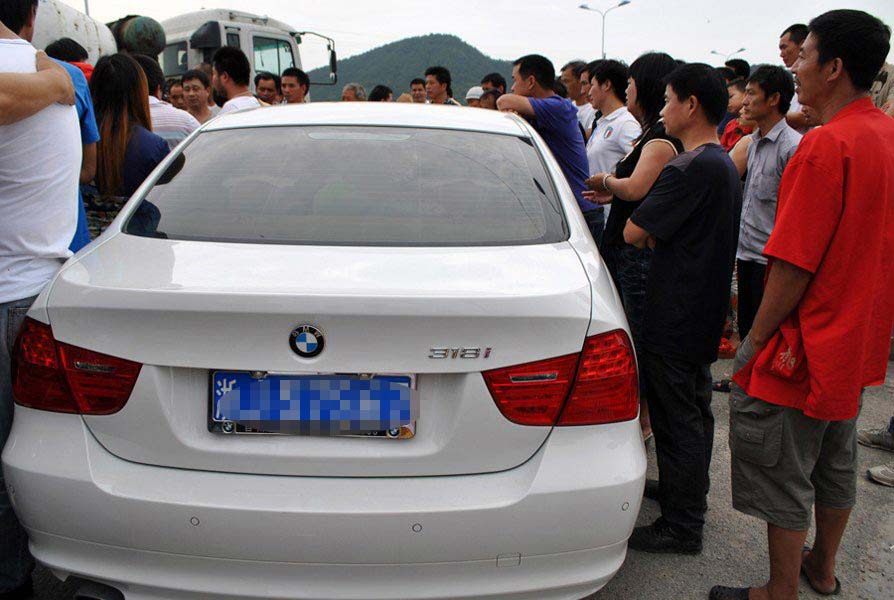 People form a crowd at the spot of a car accident. A BMW car crashed with a tricycle at the street of Wenling City, Zhejiang province on June 16, 2012. (Photo/CNTV) 