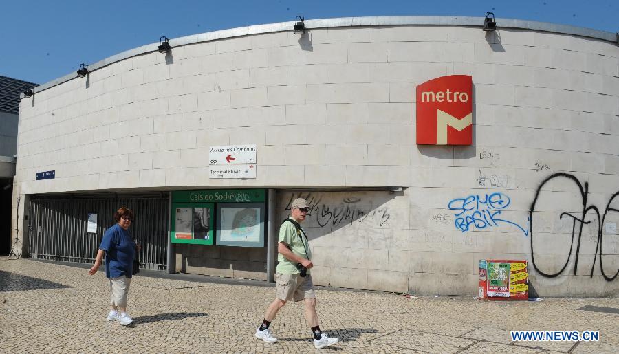 People pass by a closed metro station in Lisbon, June 27, 2013. The Portuguese staged a general strike across the country on Thursday fuelled by the prolonged economic recession in the bailed-out country. Meanwhile, thousands of Portuguese in Lisbon took to the street protesting against the government's austerity measures. (Xinhua/Zhang Liyun) 