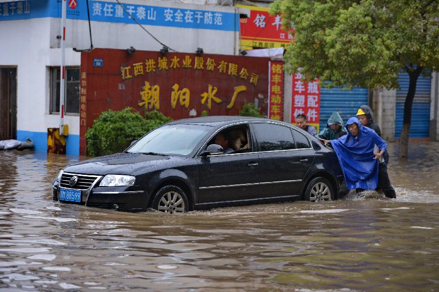 Citizens help to push a car trapped on a flooded road in Nanchang, capital of east China's Jiangxi Province, June 28, 2013. Heavy rainfall hit the city on Friday. (Xinhua/Zhou Mi)