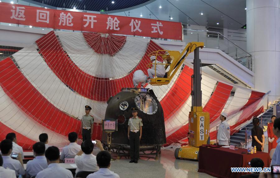 Staff members open the re-entry capsule of China's Shenzhou-10 spacecraft in Beijing, capital of China, June 28, 2013. A ceremony was held in Beijing on Friday to open the re-entry capsule of Shenzhou-10 spacecraft.(Xinhua/Tian Zhaoyun)