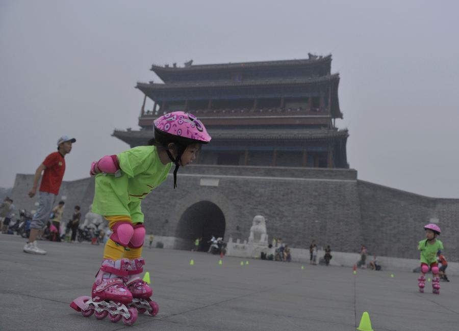 A little girl learns roller skating in haze in Beijing, capital of China, June 28, 2013. Most parts of Beijing are shrouded by severe haze on Friday. (Xinhua/Song Weiwei) 