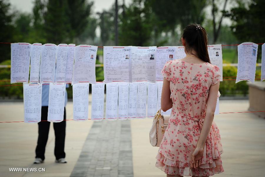 A woman reads personal information of people attending a blind date party at a park in Changchun, capital of northeast China's Jilin Province, June 30, 2013. (Xinhua/Xu Chang)
