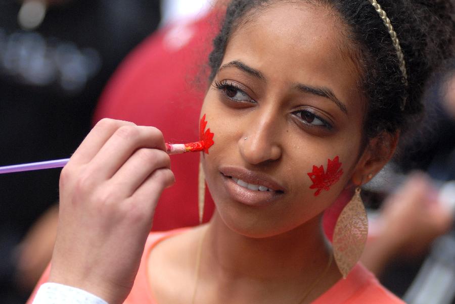 A girl gets her cheek painted with maple leaves during the Canada Day celebrations in Vancouver, Canada, on July 1, 2013. Tens of thousands of spectators flooded the streets of Vancouver to participate in Canada Day festivities. (Xinhua/Sergei Bachlakov) 