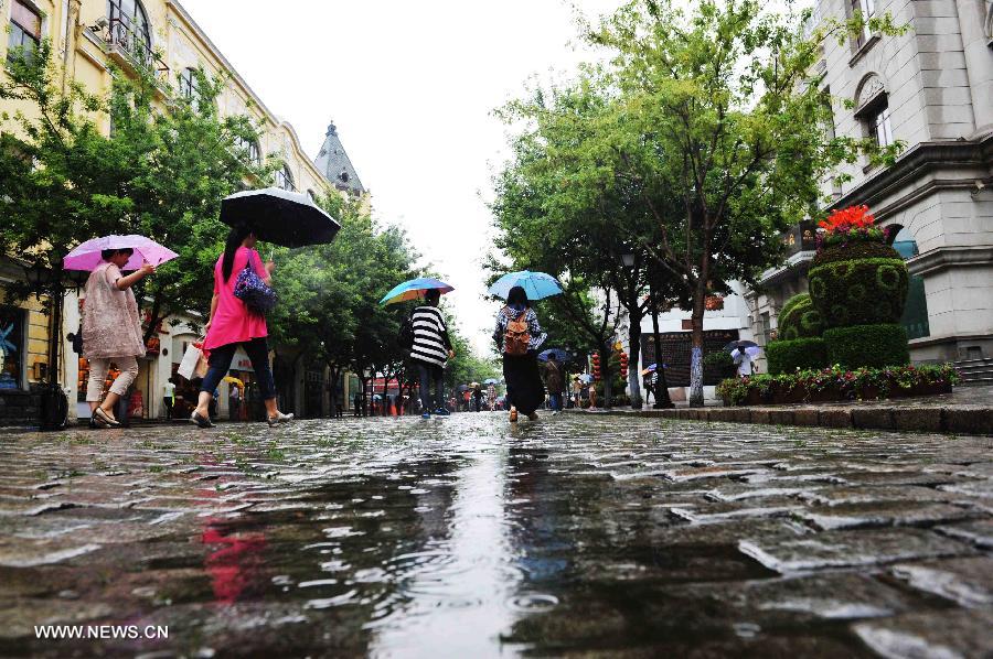 People walk on the street in Harbin, capital of northeast China's Heilongjiang Province, July 2, 2013. The local meteorological center in Heilongjiang Province issued a blue rainstorm alert on Tuesday.(Xinhua/Wang Jianwei)