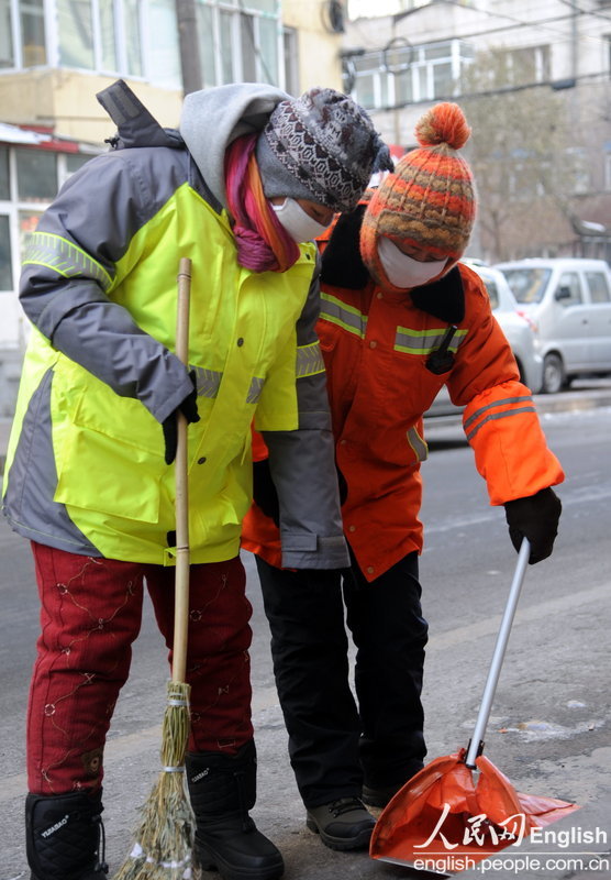 Hao Wenfang, a master degree holder born in 1983, learns cleaning skills from her team leader in Harbin, Jan. 11, 2013. More than 160 new sanitation workers began to work in Harbin. Two among them had master degrees. (Photo/CFP)