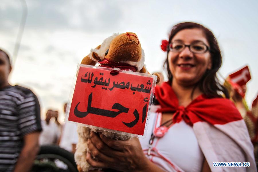 An Egyptian woman holds a sign that says "Leave" during an opposition rally in front of Al-Qoba presidential palace in Cairo, Egypt, July 2, 2013. Egyptian President Mohamed Morsi said late Tuesday that there will be no alternative for "constitutional legitimacy," amid the ongoing political division in his country, where the opposition and liberal are asking him to quit power. (Xinhua/Amru Salahuddien)