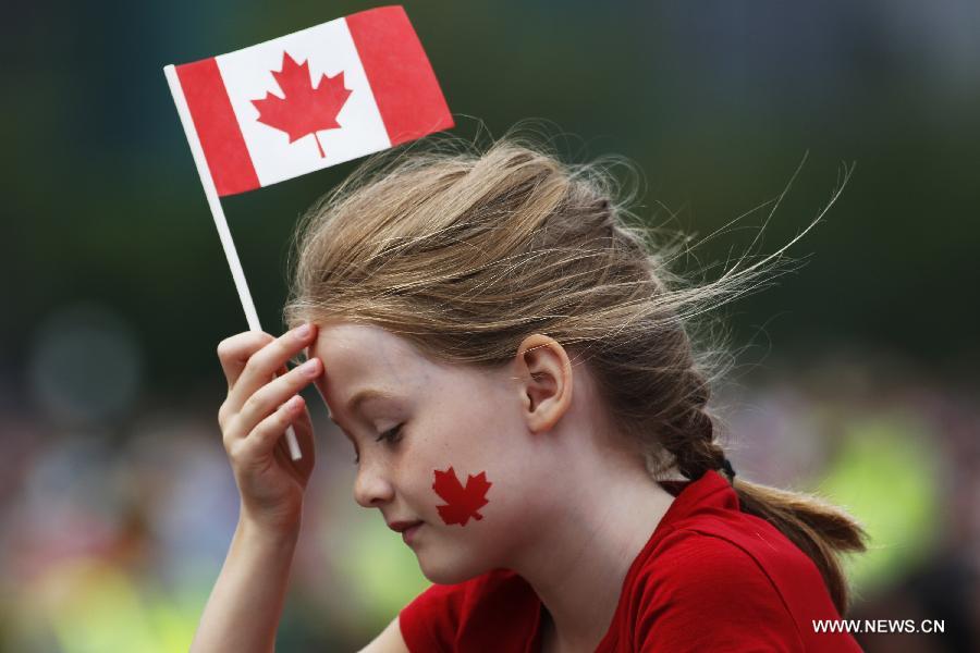 A girl holds a Canadian national flag as she waits in the crowd for the annual free concert, a part of Canada Day celebrations, in front of Parliament Hill in Ottawa, capital of Canada, on July 1, 2013. Celebrations were held across the country to mark the 146th anniversary of Canada's foundation. (Xinhua/David Kawai)