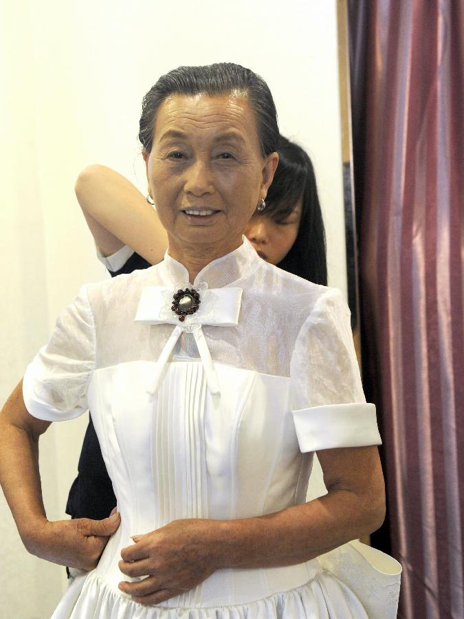 A woman tries on a wedding dress at a photography studio in Hefei, East China's Anhui province, July 4, 2013. A community in Hefei and Hefei University of Technology offered free wedding photos for 11 couples over the age of 60. The oldest couple were 80 years old. (Xie Chen/Xinhua)