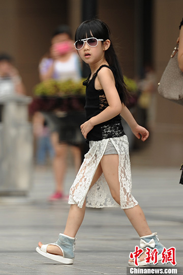 A girl wearing sunglasses and lace dress walks on a street in southwest China’s Chongqing on July 4, 2013. (CNS/Chen Chao) 