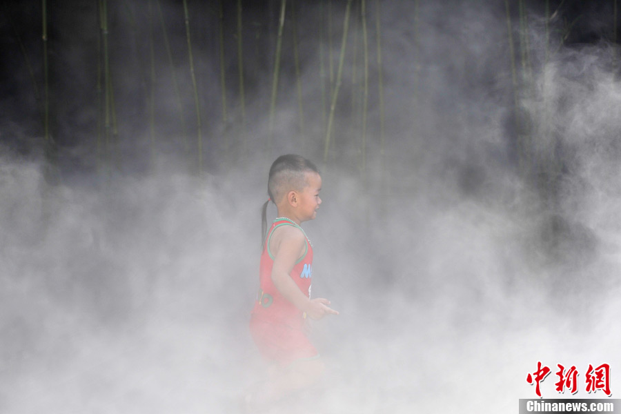 A child plays in water mist in Fuzhou on July 2, 2013. Fuzhou experienced hot temperature in recent days. Water spray equipment at Three Lanes and Seven Alleys has brought some cool feeling to local residents. (CNS/ Lyu Ming) 