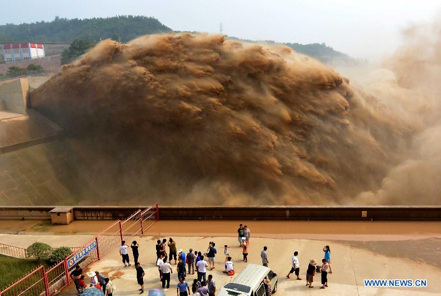 Tourists watch water gushing out from the Xiaolangdi Reservoir on the Yellow River during a sand-washing operation in Luoyang, central China's Henan Province, July 5, 2013. The on-going operation, conducted on Friday, works by discharging water at a volume of 2,600 cubic meters per second from the reservoir to clear up the sediment in the Yellow River , the country's second-longest waterway. Speeding currents would carry tons of sand into the sea. The Yellow River has been plagued by an increasing amount of mud and sand. Each year, the river bed rises as silt deposits build up, slowing the water flow in the lower reaches. (Xinhua/Wang Song) 
