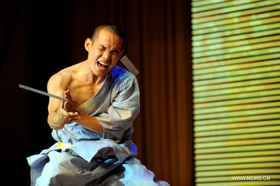 A performer of the Yandong Shaolin Kungfu troupe breaks a steel sheet by hitting his head during a performance held at the Worker's Cultural Palace, Taiyuan, capital of north China's Shanxi Province, July 6, 2013. The martial art troupe have their performers trained in the renowned Shaolin Temple, and staged performances worldwide in the hope of promoting Shaolin-style martial arts and Chinese culture. (Xinhua/Fan Minda) 