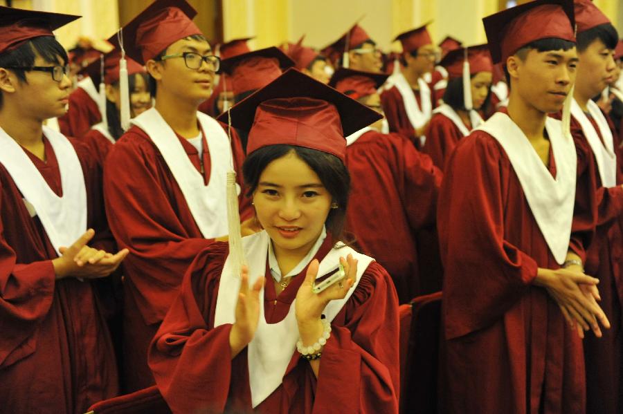 Graduates stand up and applaud during the graduation ceremony held by Beijing Concord College of Sino-Canada for its senior high graduates in Beijing, capital of China, July 6, 2013. A total of 303 senior high students graduate from Beijing Concord College of Sino-Canada this year, among which ten were admitted by universities in China, other 293 were accepted by universities from abroad, according to the school authority. (Xinhua/Lu Peng)