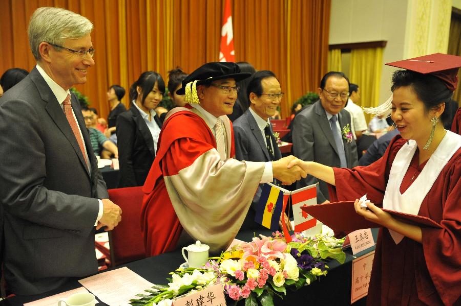 Honored guests deliver diplomas for graduates during the graduation ceremony held by Beijing Concord College of Sino-Canada for its senior high graduates in Beijing, capital of China, July 6, 2013. A total of 303 senior high students graduate from Beijing Concord College of Sino-Canada this year, among which ten were admitted by universities in China, other 293 were accepted by universities from abroad, according to the school authority. (Xinhua/Lu Peng)