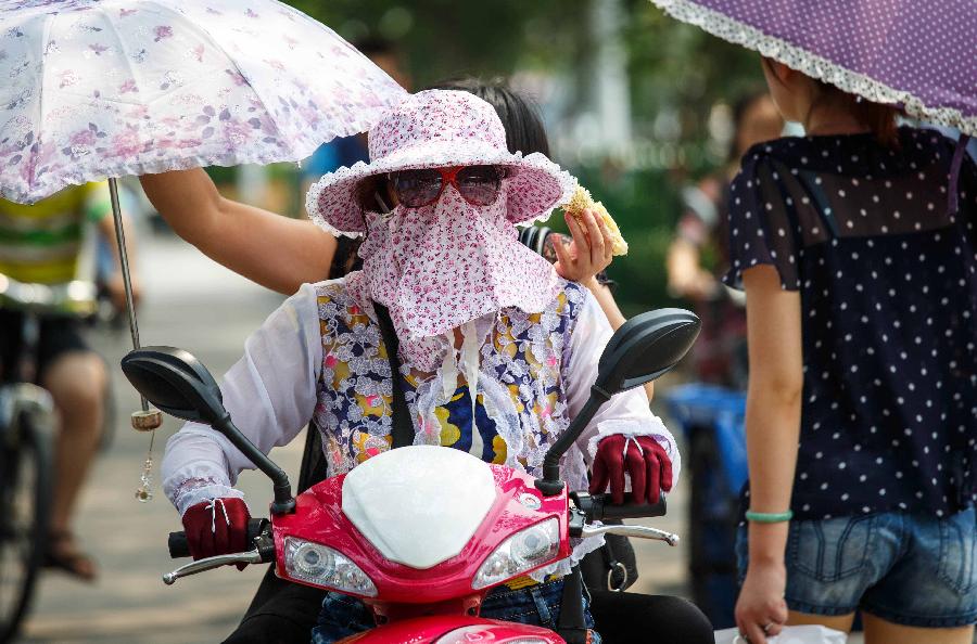 A citizen rides in a street in Nantong City, east China's Jiangsu Province, July 8, 2013. The rainy season ends on Monday July 8 and high temperature may hit 36 degrees Celsius in a few days in the southern Huaihe River region in east China's Jiangsu Province, according to the local meteorological observatory. (Xinhua/Huangzhe)