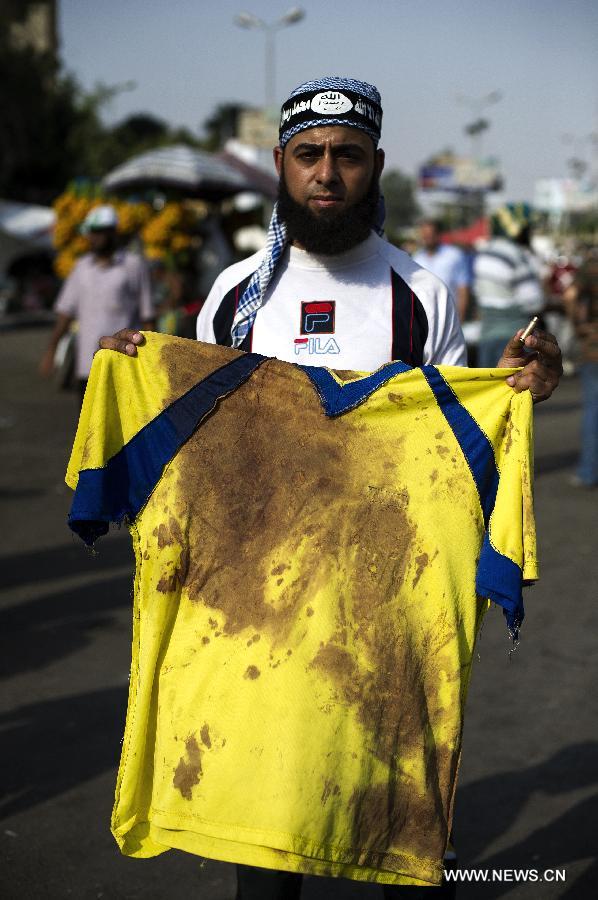 A supporter of ousted Egyptian president Mohamed Morsi displays a blood-stained cloth and a bullet shell outside Raba al-Adwyia Mosque, in Nasr City, Cairo, capital of Egypt, July 8, 2013. (Xinhua/Li Muzi)