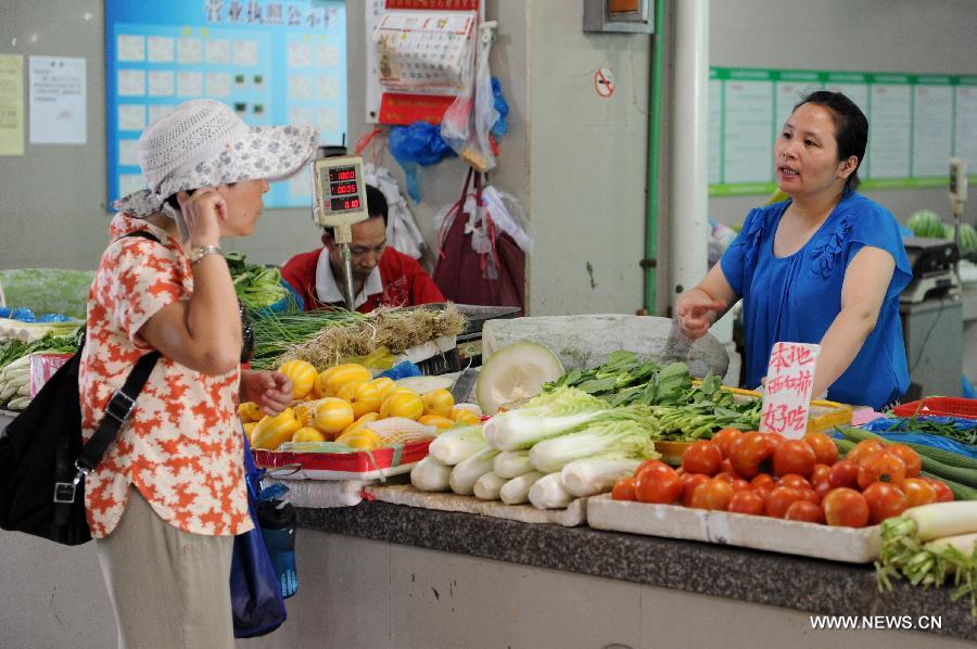 A seller talks with a consumer at a market in Hangzhou, capital of east China's Zhejiang Province, July 9, 2013. China's consumer price index (CPI), a main gauge of inflation, grew 2.7 percent year on year in June, up from 2.1 percent in May, the National Bureau of Statistics said on Tuesday. (Xinhua/Ju Huanzong) 