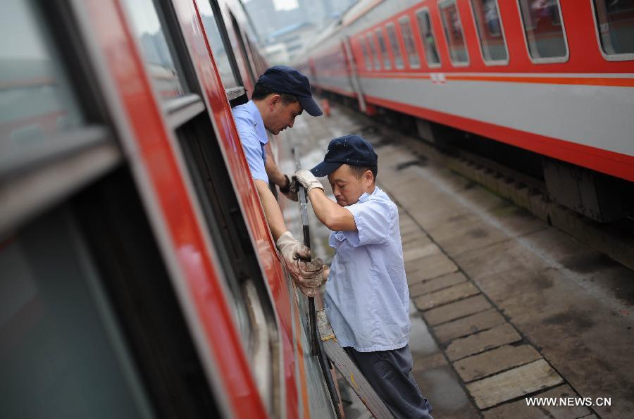 Staff members from the maintenace crew examine the windows of a train in Chengdu, capital of southwest China's Sichuan Province, July 8, 2013. Known as the "Train Hospital", the maintenance crew provide 24-hour-services for examining and cleaning trains. (Xinhua/Xue Yubin)