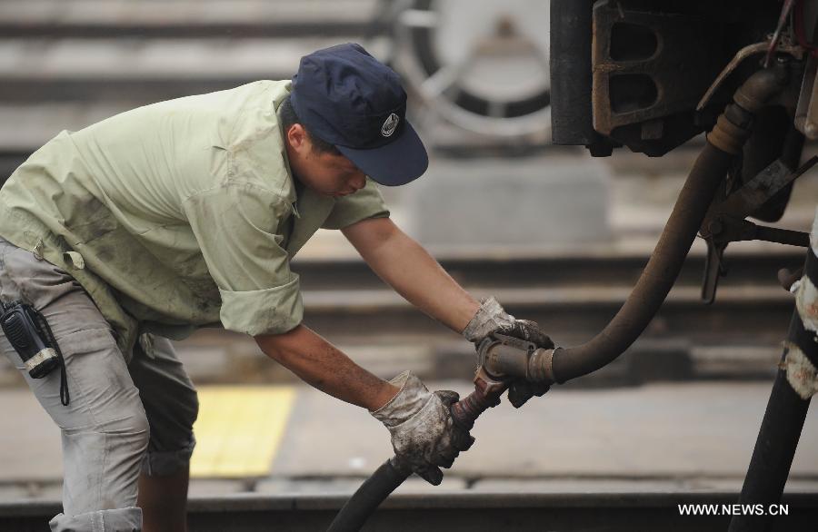 A staff member from the maintenace crew examines the braking system of a train in Chengdu, capital of southwest China's Sichuan Province, July 8, 2013. Known as the "Train Hospital", the maintenance crew provide 24-hour-services for examining and cleaning trains. (Xinhua/Xue Yubin)