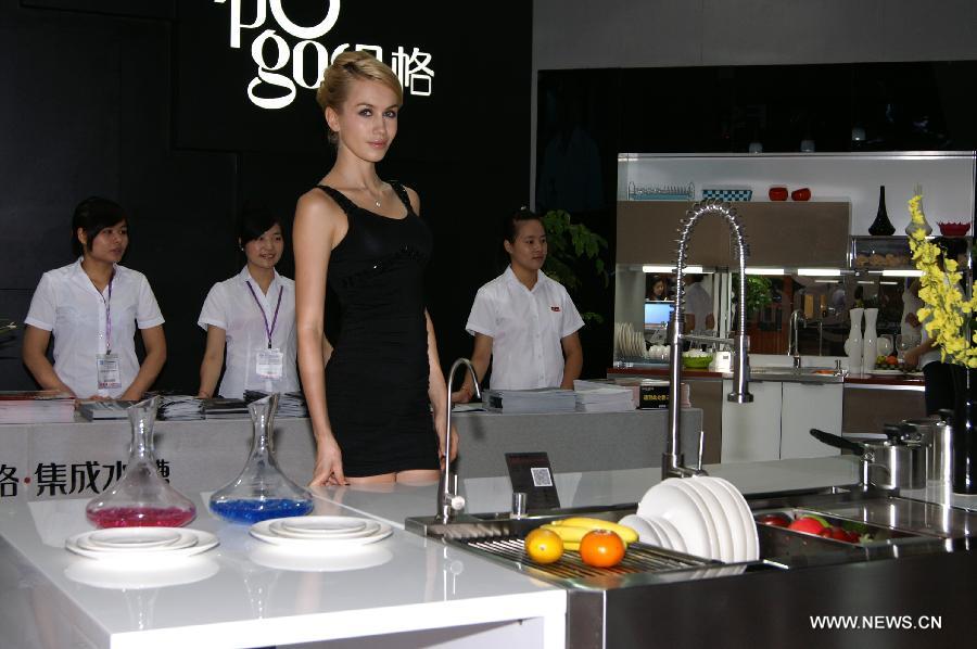 A model displays kitchenwares at the 2013 China (Guangzhou) International Building Decoration Fair in Guangzhou, capital of south China's Guangdong Province, July 8, 2013. More than 2,000 enterprises from across the world took part in the four-day fair, opened on Monday. (Xinhua/Gong Hui)