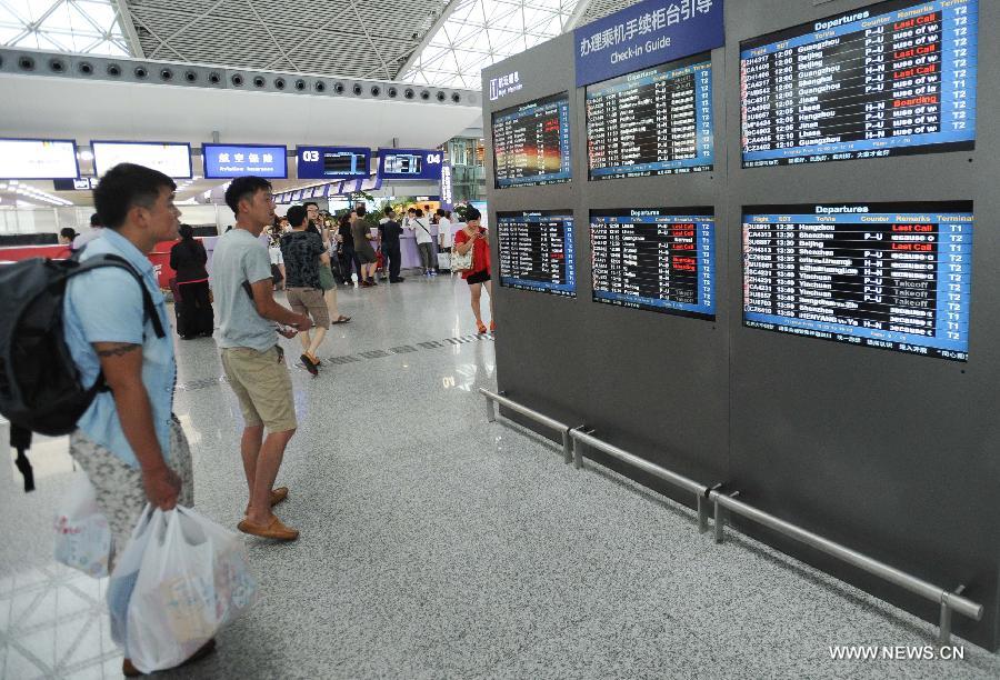 Passengers read flight information at the Shuangliu International Airport in Chengdu, capital of southwest China's Sichuan Province, July 9, 2013. More than 4,000 passengers were stranded at the airport Tuesday due to the rainstorm in Chengdu. (Xinhua/Li Qiaoqiao) 
