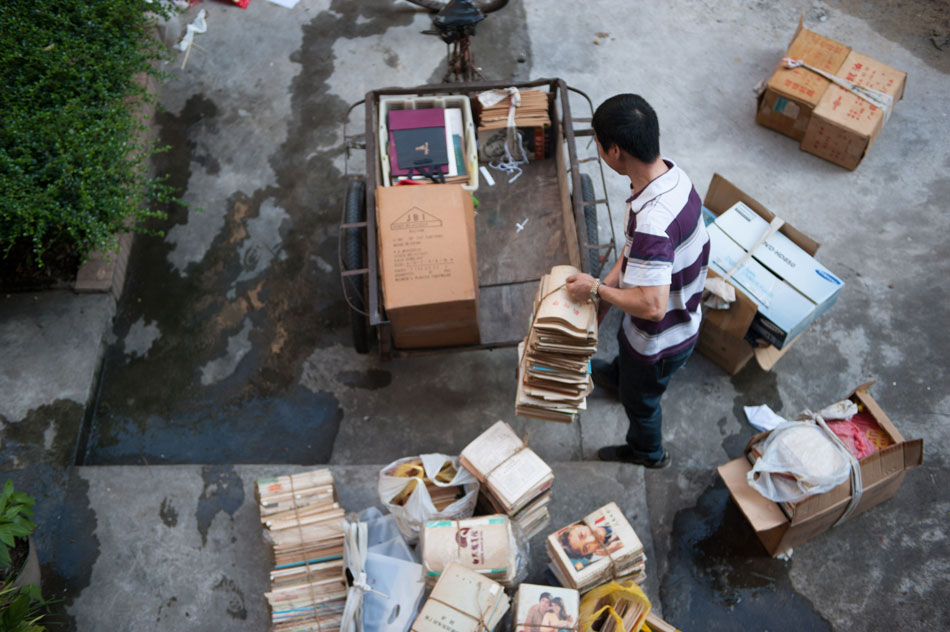 You Manqin moves books he recycled in a university on to a trike, Guangzhou, June 30, 2013. You has two identities. On weekdays, he is an apprentice lawyer, but on weekends he goes back to do the familiar work of collecting garbage. In 2012, You passed the national judicial examination, the test for lawyer qualification which is famed for the difficulty and the low passing rate in China. (Xinhua/Mao Siqian)
