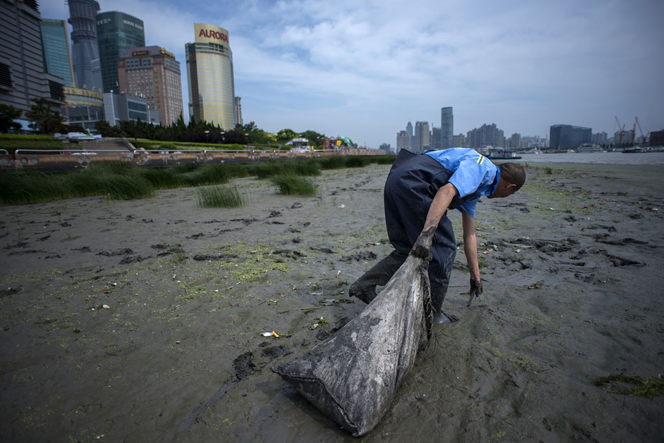Sanitation worker Hu Yuanbao cleans the waste left on tidal flat of the Huangpu River in Shanghai, July 4, 2013. (Xinhua/Wu Zixi)