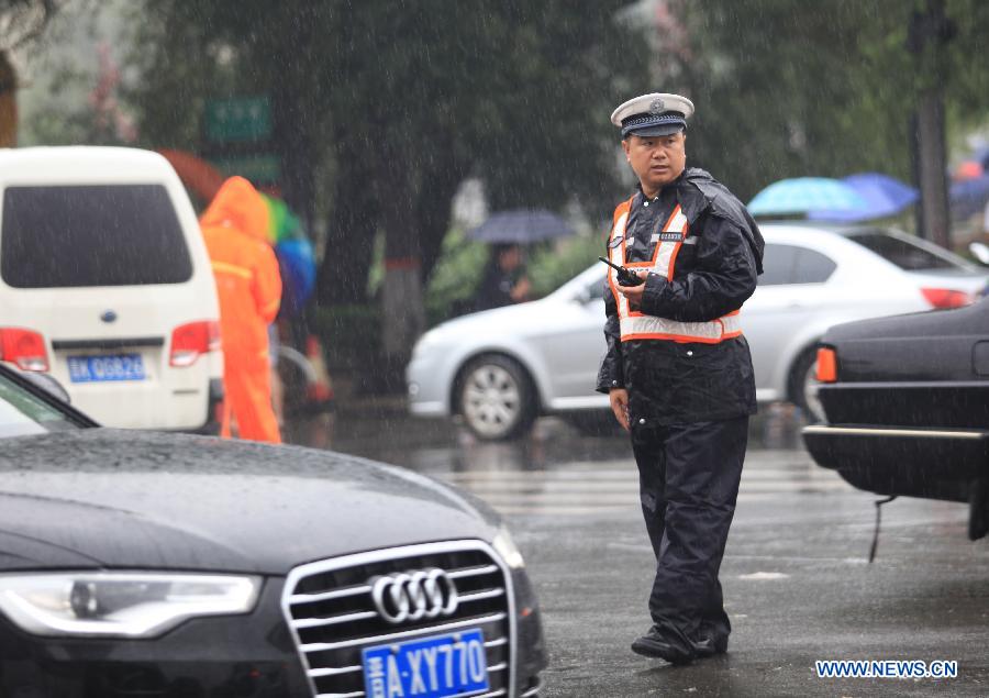 A policeman directs traffic on the flooded Nanneihuan Street in Taiyuan City, capital of north China's Shanxi Province, July 9, 2013. A heavy rainfall hit many regions of Shanxi Province on Tuesday. Parts of Taiyuan City was seriously flooded and the traffic was disrupted. (Xinhua/Shi Xiaobo)