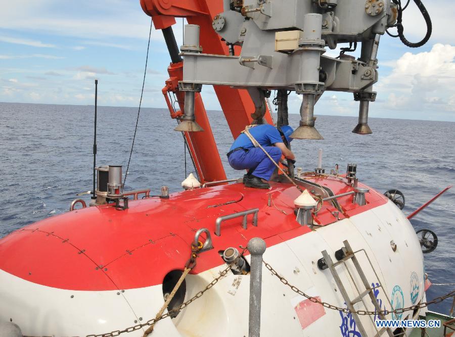 Staff member Gao Xiang ties a rope on China's manned submersible Jiaolong in the South China Sea, south China, July 10, 2013. The Jiaolong manned submersible on Wednesday carried out the last scientific dive to explore the geology and environment of the sea area. (Xinhua/Zhang Xudong)