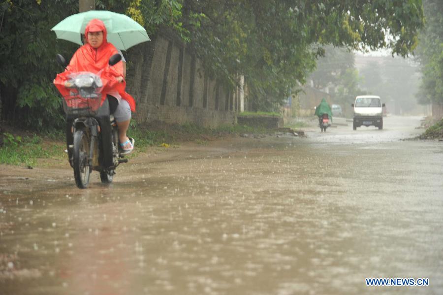 People ride in rain in Xinjiang County of Yuncheng City, north China's Shanxi Province, July 10, 2013. Heavy rainfall hit many parts of Shanxi from Tuesday night. (Xinhua/Gao Xinsheng)