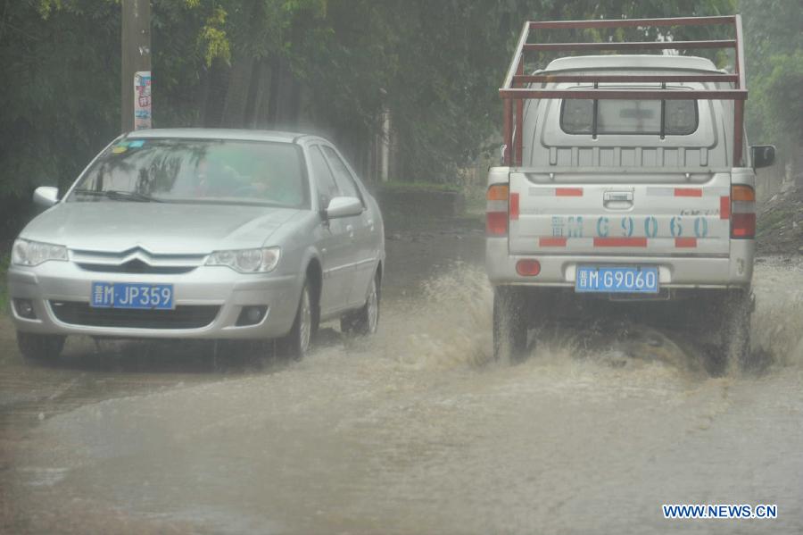 Vehicles run in rain in Xinjiang County of Yuncheng City, north China's Shanxi Province, July 10, 2013. Heavy rainfall hit many parts of Shanxi from Tuesday night. (Xinhua/Gao Xinsheng)